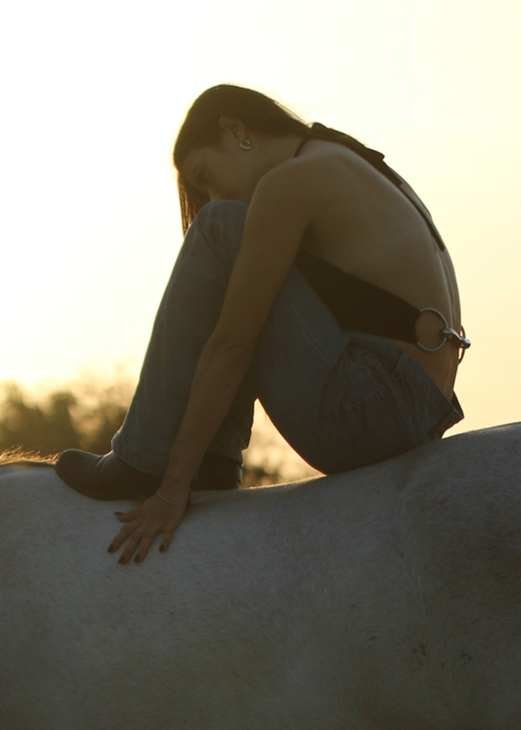 Model wearing Bit Top in black on a horse from the side